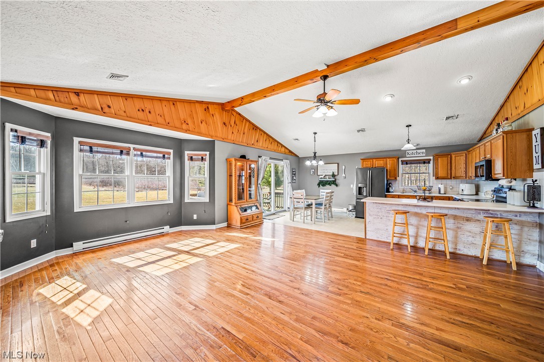 7290 Turner Road Pierpont, OH 44082 - Photo 5 of 36 Kitchen featuring a baseboard radiator, stainless steel appliances, light hardwood / wood-style floors, a breakfast bar, and lofted ceiling with beams