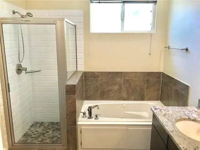 a bathroom with a granite countertop sink and a bathtub