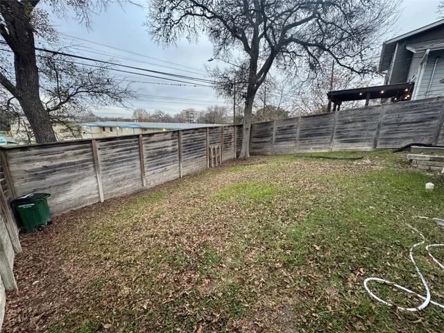 a view of a backyard with wooden fence and large trees
