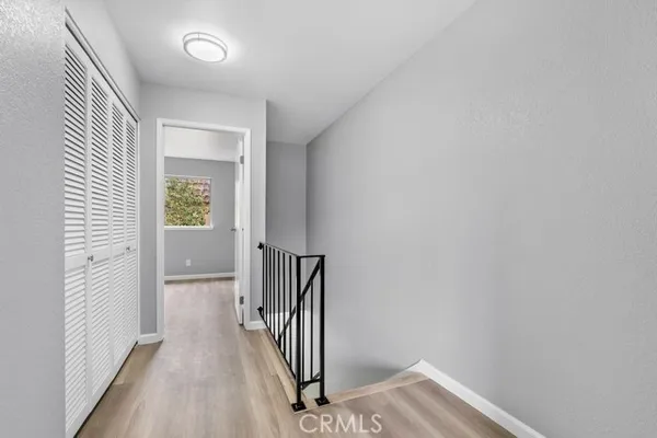 a view of a hallway with wooden floor and a bathroom