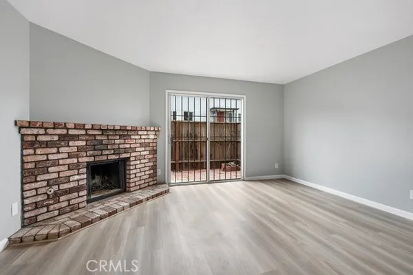 an empty room with wooden floor fireplace and windows