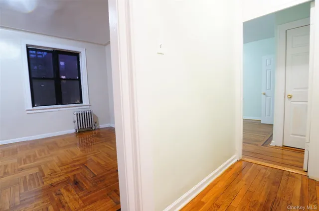 a view of an empty room with wooden floor and a bathroom