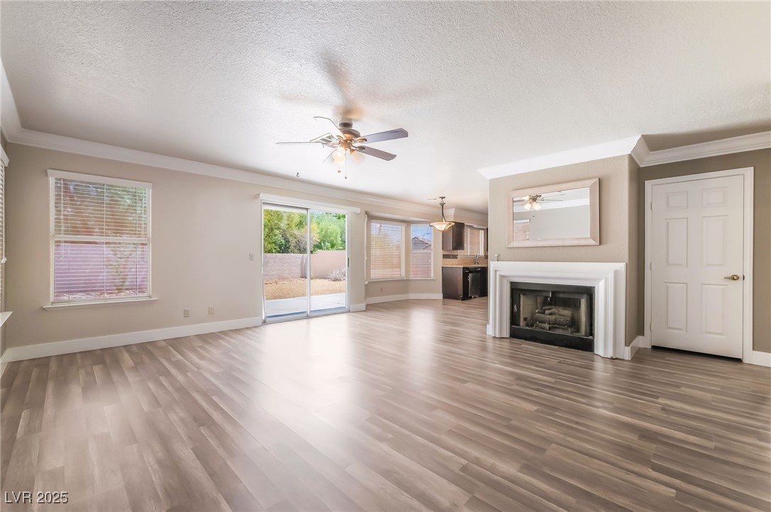 1804 Michaels Court Henderson, NV 89014 - Photo 13 of 44 Unfurnished living room featuring ceiling fan, ornamental molding, a fireplace, a textured ceiling, and wood finished floors