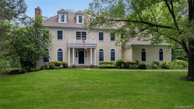 a view of a white house with a big yard and large trees