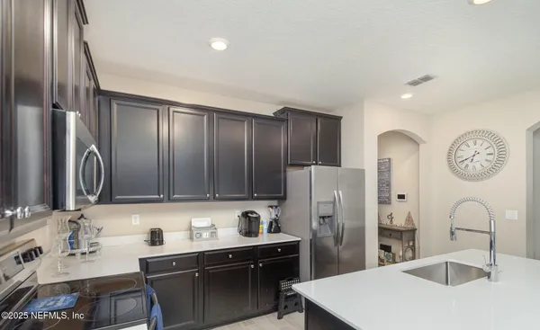 a kitchen with stainless steel appliances a sink a stove a refrigerator cabinets and a dining table