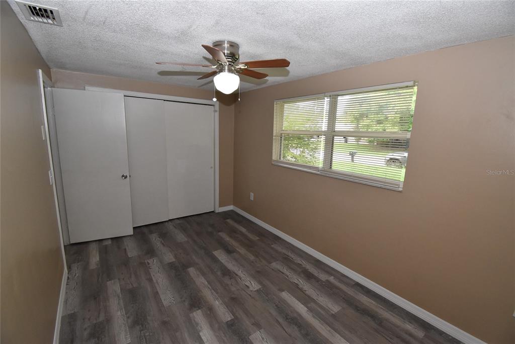 7524 Galahad Road Port Richey, FL 34668 - Photo 20 of 26 an empty room with wooden floor fan and windows