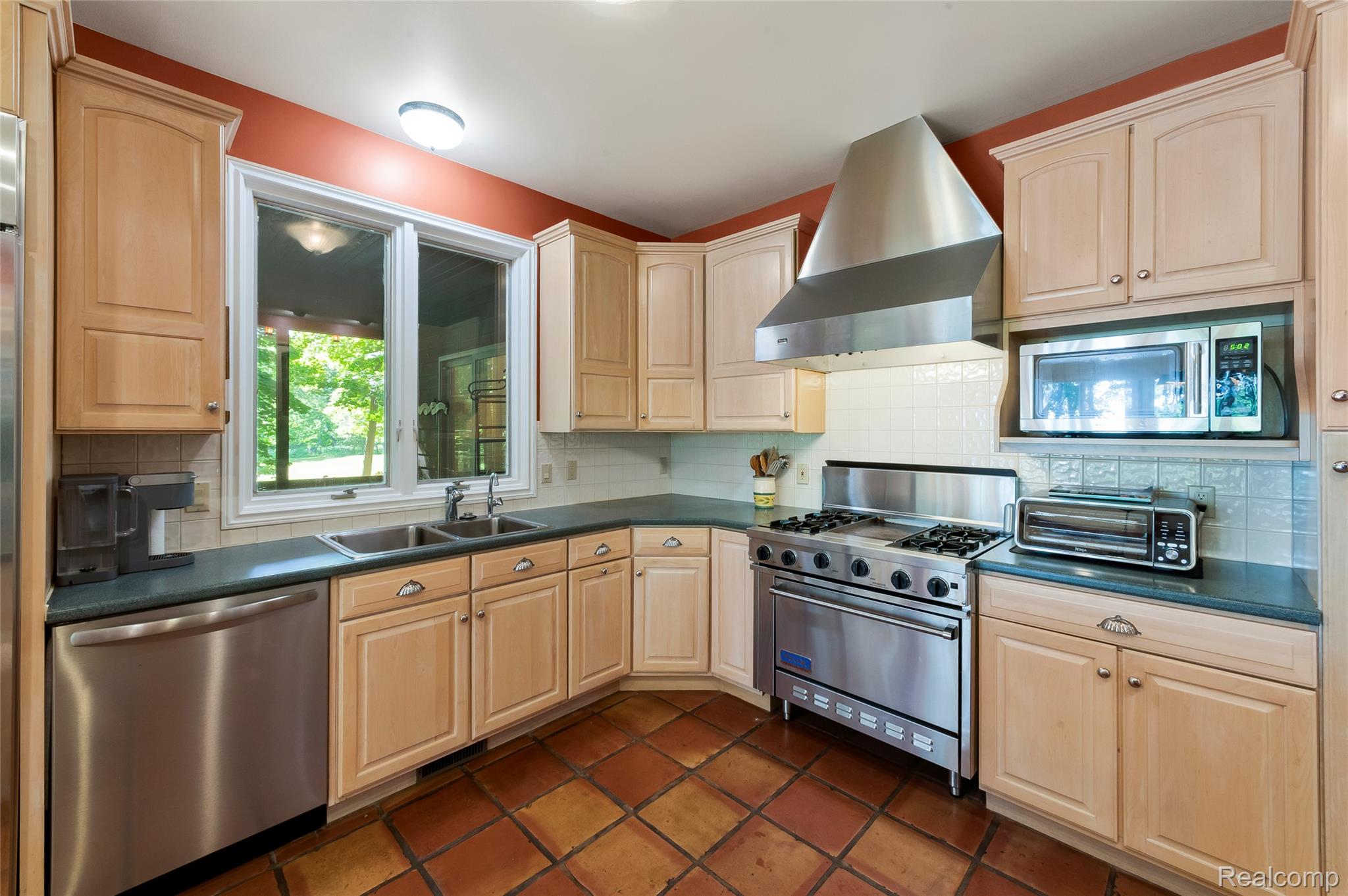 2323 Addaleen Road Highland, MI 48357 - Photo 38 of 70 Kitchen featuring light wood cabinetry, a stainless steel range with a professional-grade hood, a double basin sink, and terracotta tile flooring