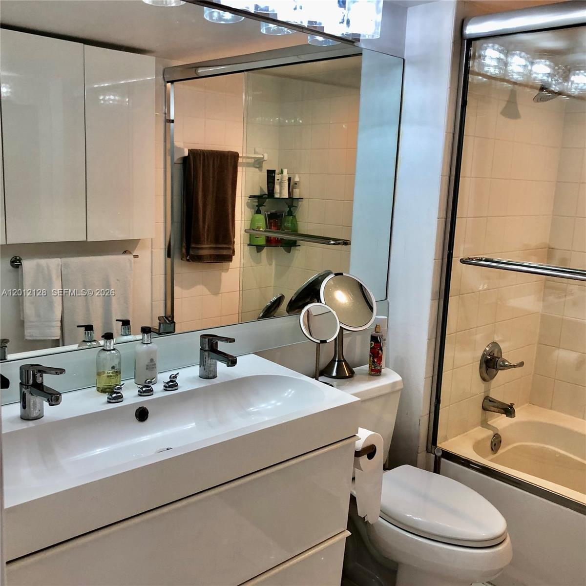90 Alton Road, Unit 307 Miami Beach, FL 33139 - Photo 9 of 11 a bathroom with a sink a toilet a mirror and shower
