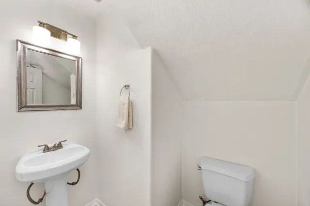 a bathroom with a toilet sink vanity and mirror