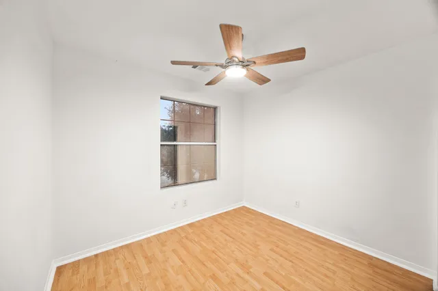 an empty room with a window and ceiling fan