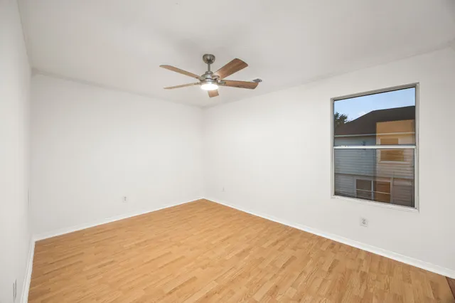 an empty room with a window and a ceiling fan