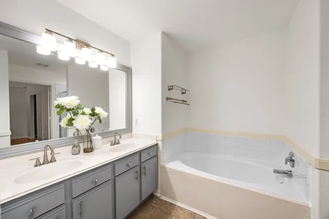 a bathroom with a tub a sink and mirror