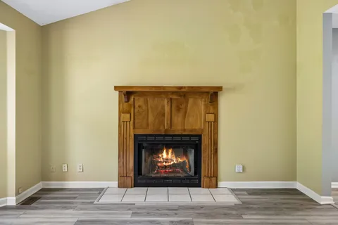a view of an empty room with wooden floor and a fireplace