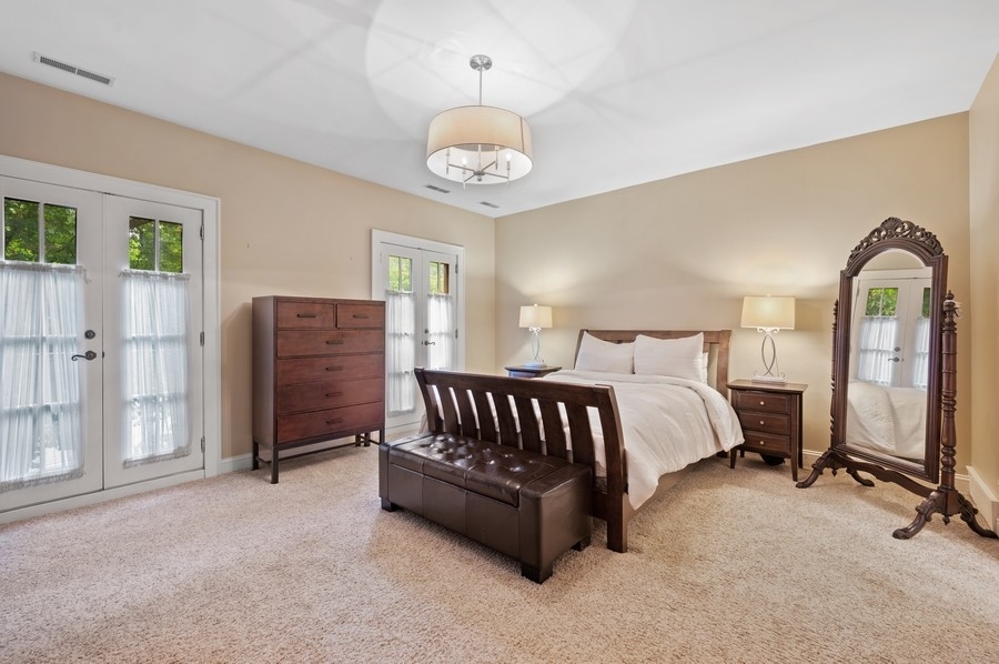 501 Ridge Road Kenilworth, IL 60043 - Photo 19 of 46 a spacious bedroom with a bed and a chandelier