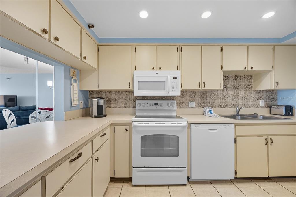 13720 Gulf Boulevard, Unit 609 Madeira Beach, FL 33708 - Photo 15 of 40 a kitchen with cabinets appliances a sink and a counter top space