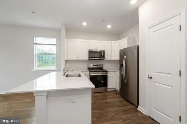 a kitchen with stainless steel appliances granite countertop a sink stove microwave and refrigerator
