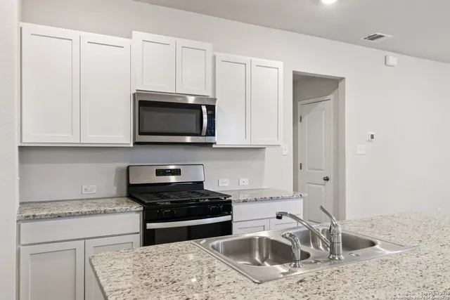 a kitchen with granite countertop a sink a stove and cabinets