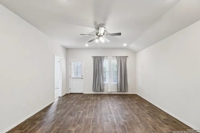 an empty room with wooden floor and ceiling fan