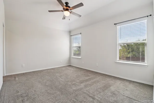 an empty room with windows and fan