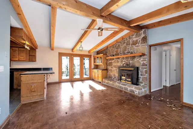 a view of an empty room with wooden floor fireplace and a window