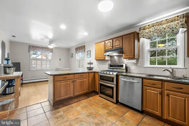 a kitchen with stainless steel appliances granite countertop sink stove top oven and cabinets