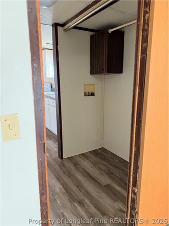 a view of an empty room with wooden floor and closet