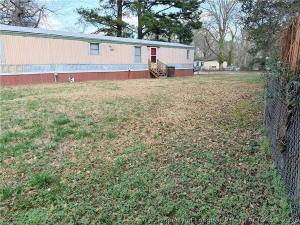 a view of a backyard with a large tree and wooden fence