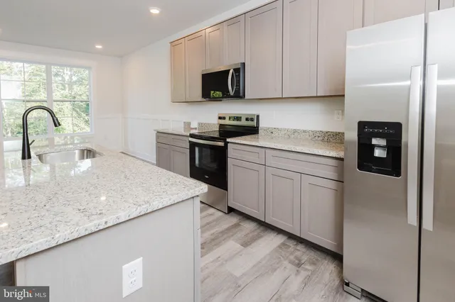 a kitchen with stainless steel appliances granite countertop a sink a stove and a refrigerator with wooden floor