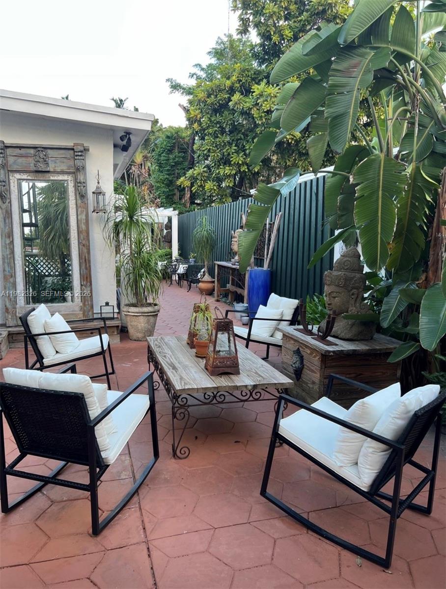 2190 Southwest 22nd Terrace Miami, FL 33145 - Photo 26 of 37 a view of a patio with couches and a table and chairs with floor to ceiling window and tree
