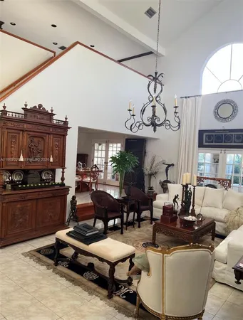 a living room with furniture a chandelier and a floor to ceiling window