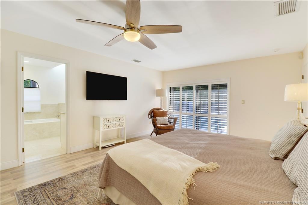 5701 Southeast Winged Foot Drive Stuart, FL 34997 - Photo 21 of 47 a bedroom with a bed and a flat tv screen on dresser
