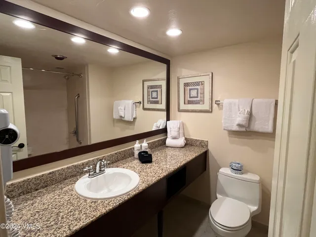 a bathroom with a granite countertop sink mirror vanity and toilet
