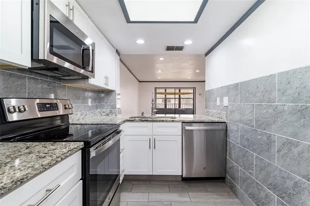 a kitchen with stainless steel appliances granite countertop a stove microwave and refrigerator