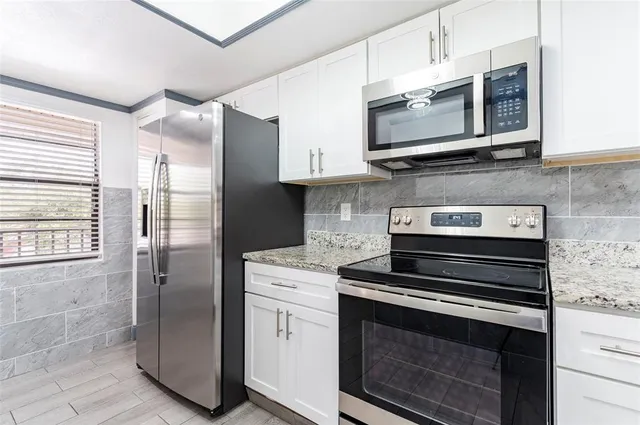a bathroom with a granite countertop sink a toilet a mirror and shower