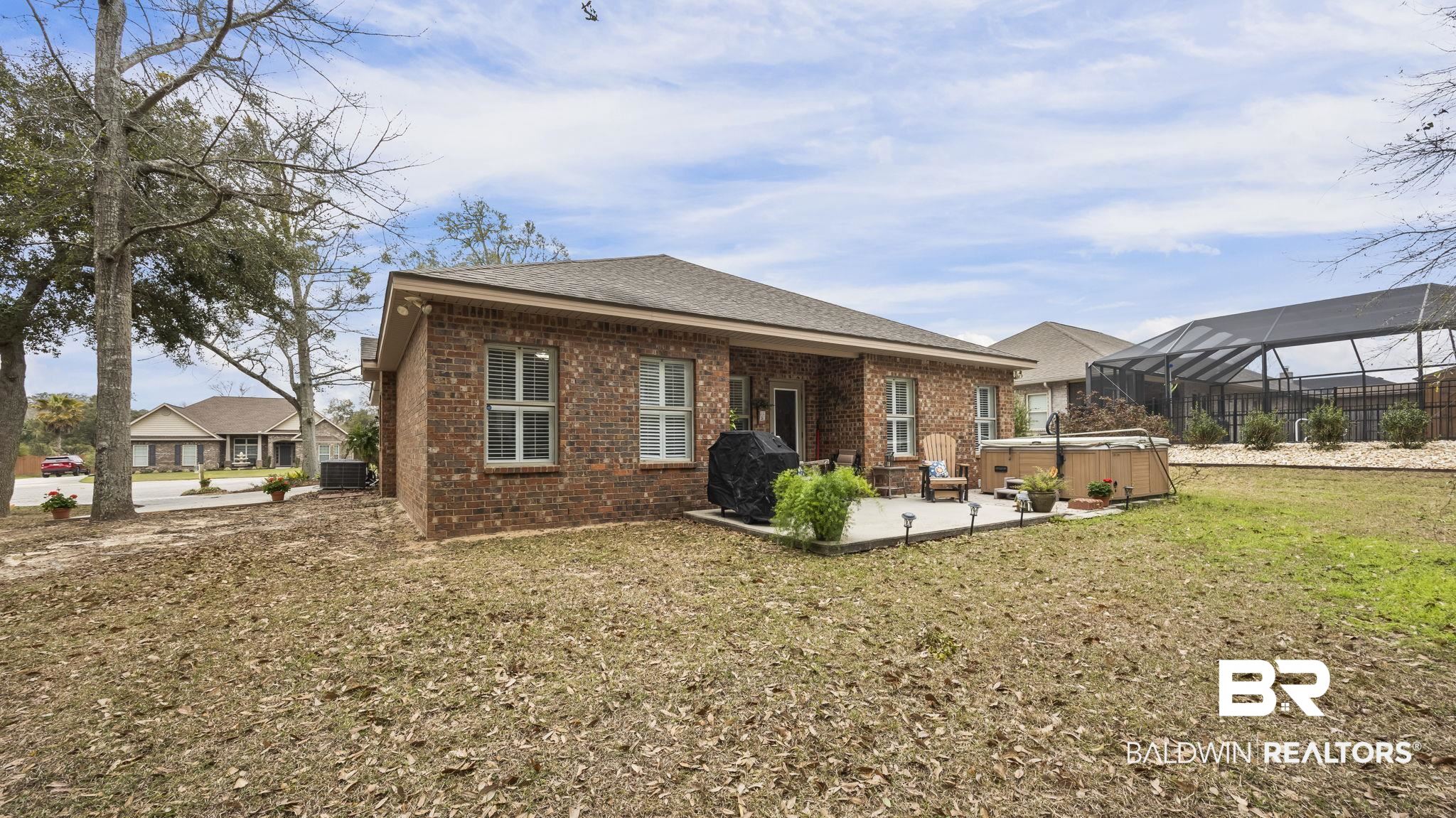 1090 Melbourne Court Foley, AL 36535 - Photo 6 of 38 Back of property featuring a hot tub, brick siding, a sunroom, a patio, and a shingled roof