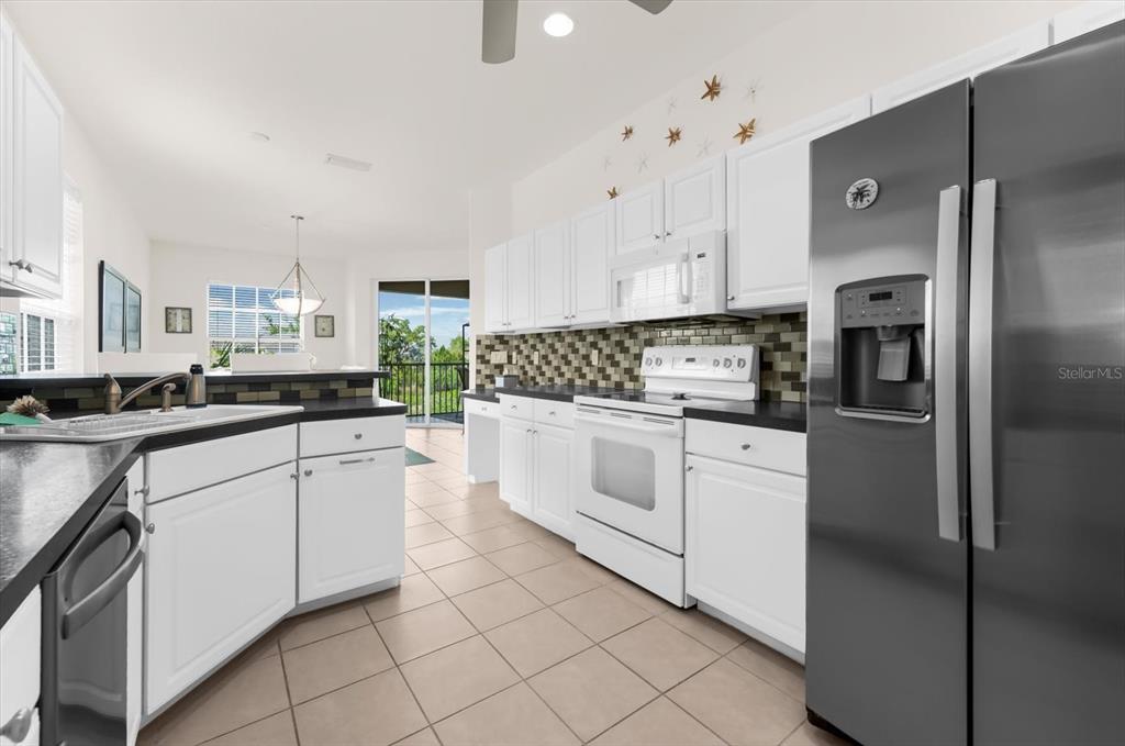 4500 Streamside Court, Unit 1408 Sarasota, FL 34238 - Photo 32 of 73 a kitchen with white cabinets and white appliances