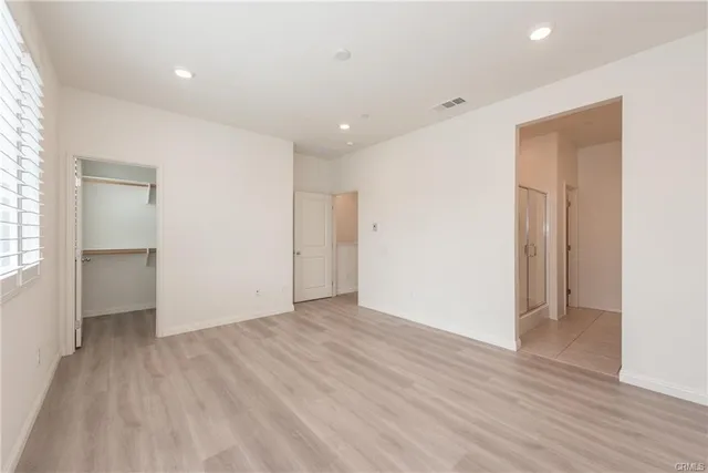 a view of an empty room with wooden floor and closet
