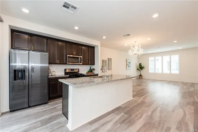 a kitchen with stainless steel appliances granite countertop a refrigerator a sink dishwasher a stove and a refrigerator with wooden floor