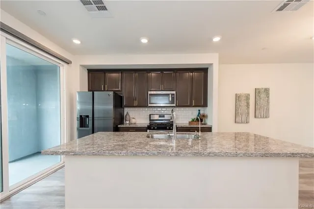 a kitchen with stainless steel appliances granite countertop a sink a stove and a refrigerator