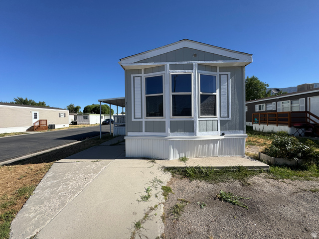 2491 Highway 89, Unit 315 Pleasant View, UT 84404 - Photo 8 of 34 Light gray exterior with white trim, featuring a prominent bay window with multiple panes