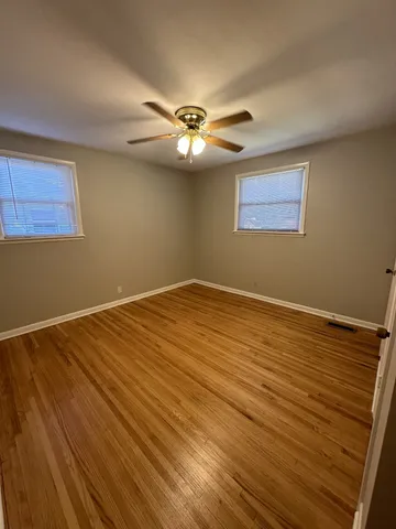 a view of an empty room with window and chandelier fan