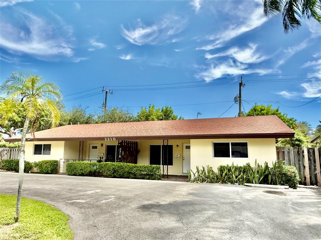 2210 Northeast 54th Street, Unit W Fort Lauderdale, FL 33308 - Photo 19 of 21 a front view of a house with a yard and potted plants