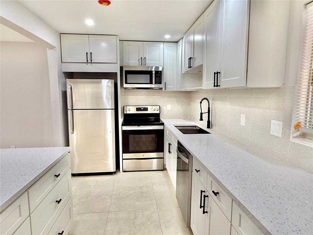 2210 Northeast 54th Street, Unit W Fort Lauderdale, FL 33308 - Photo 6 of 21 a kitchen with stainless steel appliances a refrigerator sink and cabinets