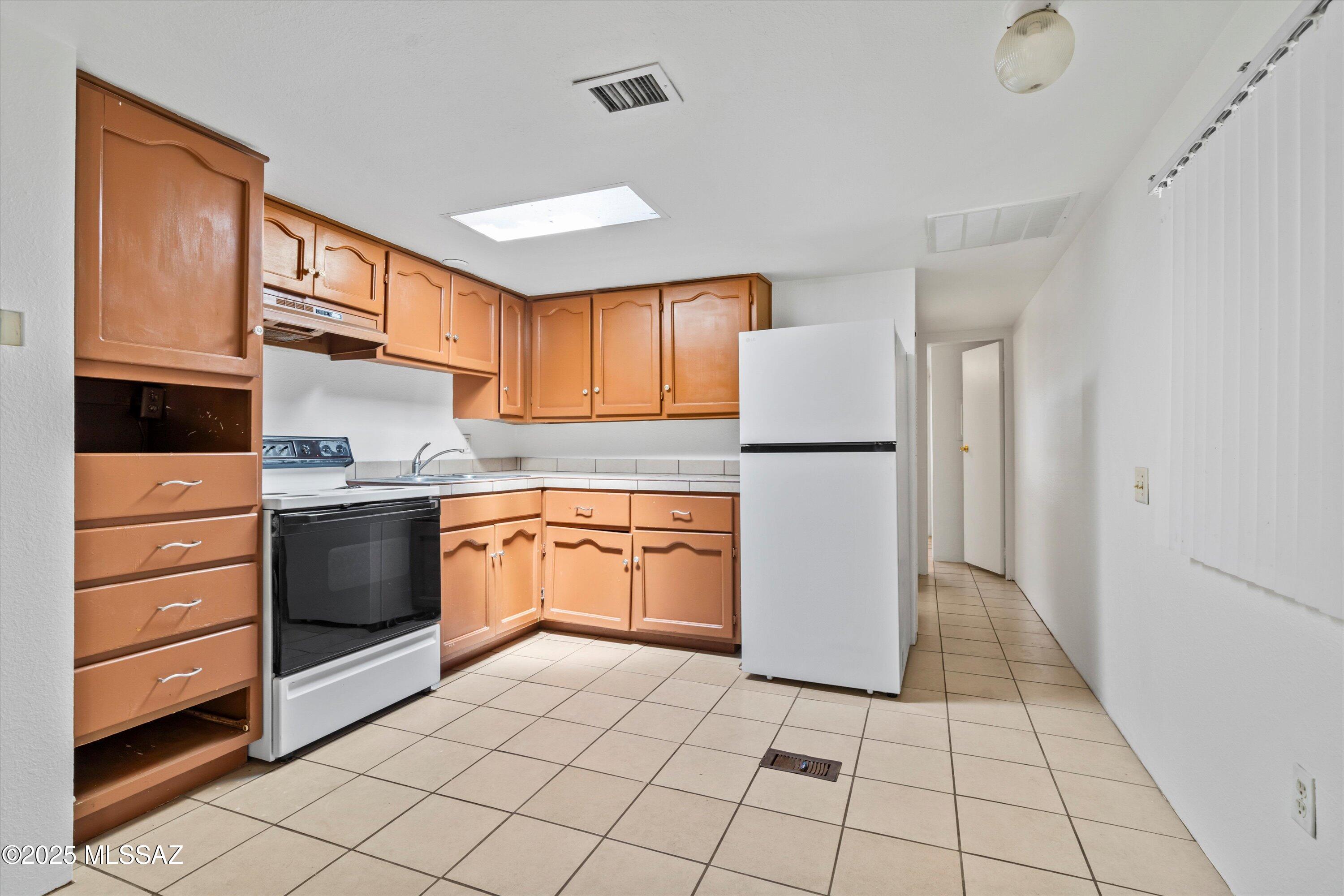 1227 East Ginter Road Tucson, AZ 85706 - Photo 13 of 18 a kitchen with a refrigerator a stove top oven and cabinets