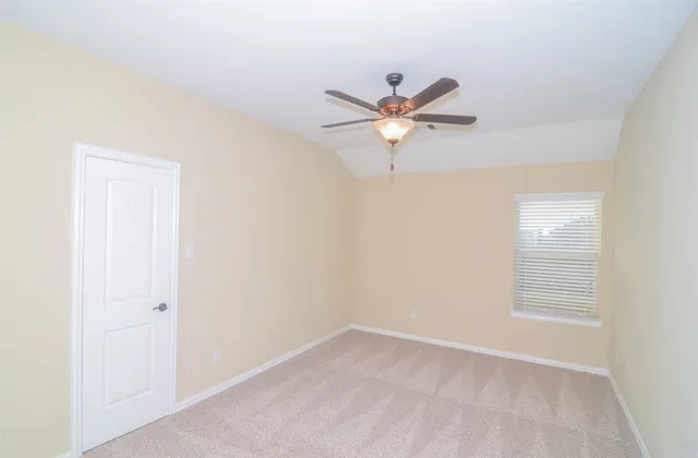 an empty room with a window and a fan
