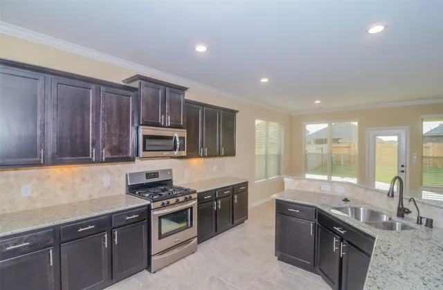 a large kitchen with stainless steel appliances granite countertop a stove and a sink