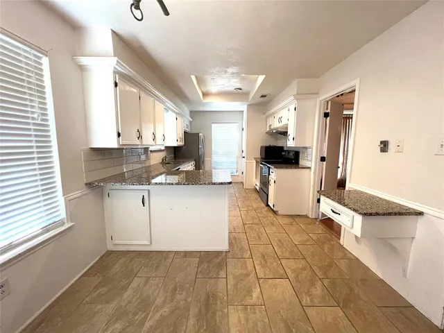 a kitchen with granite countertop a stove a sink and a refrigerator