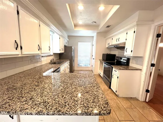 a open kitchen with stainless steel appliances granite countertop a refrigerator and a stove