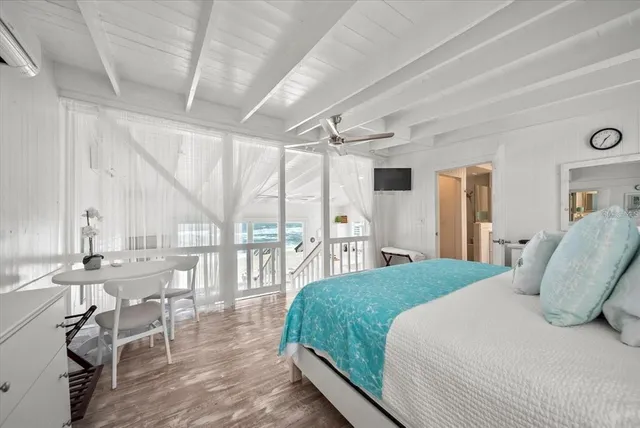 a living room with furniture large windows and wooden floor