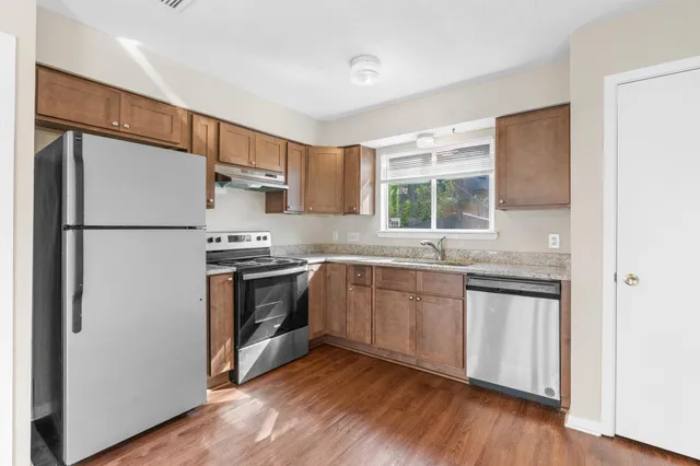 a kitchen with granite countertop a refrigerator a sink and a stove top oven